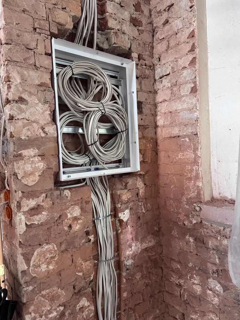 Skrzynka instalacyjna i okablowanie w odsłoniętej ścianie z cegły — realizacja Avoltaic